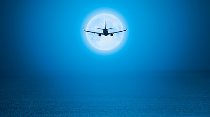 Passenger airplane in the sky against blue full moon 