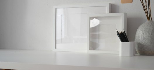 Obraz na płótnie Canvas Minimal workspace with mock up frame and copy space, white desk and white wall