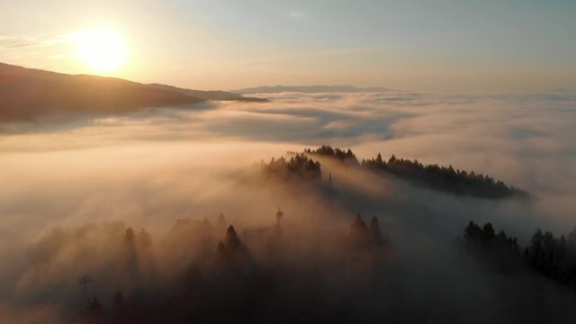 aerial shot of mountain top covered in clouds at sunrise with golden light