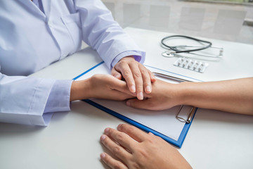 The female doctor uses a friendly hand to hold the patient's hand to give confidence and show care about health care. Medical concepts and good health