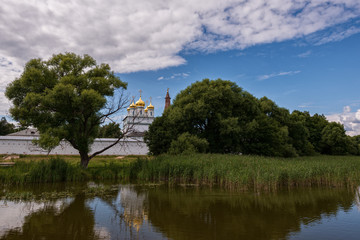 Fototapeta na wymiar View of the central Cathedral from the side of the lake between the trees. Russian shrines. Joseph-Volotsky Monastery in Teryaev. Moscow region, Teryaevo.