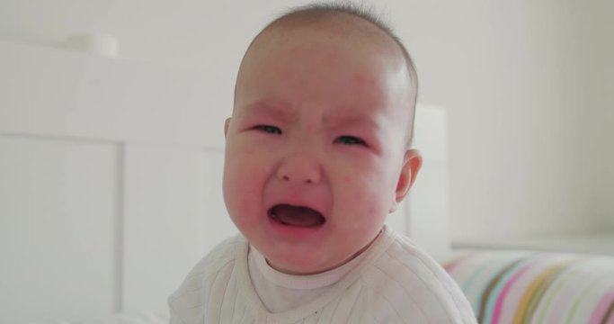 Close up of crying unhappy asian baby girl at home tears on the baby face