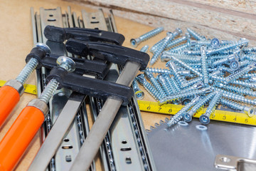 Screws, confirmations for furniture, tape measure, clamp, lie on the table. Furniture production