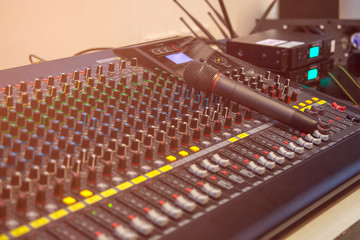 Microphone placed on the sound mixer with orange flare at the audio control room.