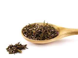 Dried Heather flowers lie in a wooden spoon on a white background