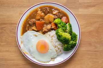 Chicken curry Rice on wooden background ( Poached egg, Potato, enoki mushroom, onion, broccoli, Japanese style,)