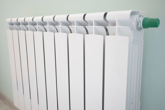 Radiator with thermostat valve isolated on green background