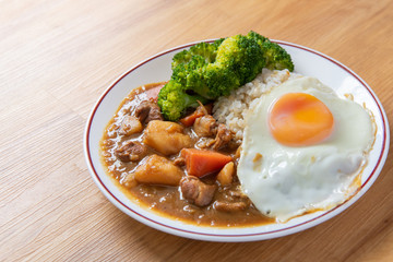 Chicken curry Rice on wooden background ( Poached egg, Potato, enoki mushroom, onion, broccoli, Japanese style,)
