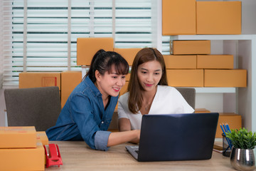 Two Asian teenager owner business woman work sitting on the table for online shopping, checking order  for delivery mail shipping with office equipment, entrepreneur lifestyle concept