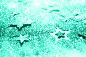 Fototapeta na wymiar Christmas celebration. Abstract background for new year party. Patter of gold stars with lights, bokeh. Trendy green and turquoise color. Glitter stars in mint color