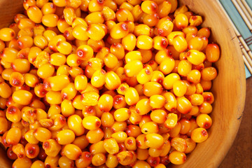Ripe berries of sea buckthorn in a wooden plate