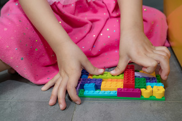 A girl is playing with colorful plastic jigsaw toys and brick sets.