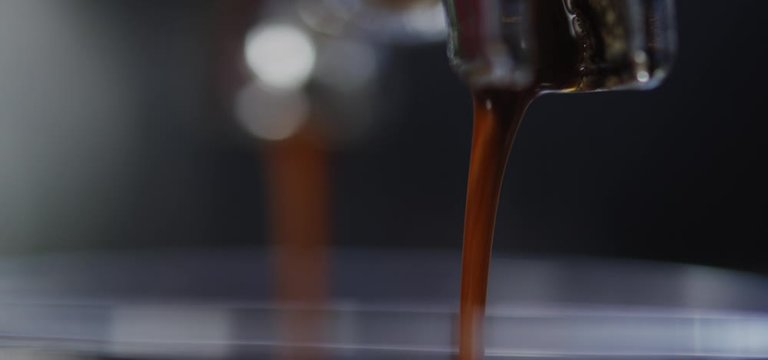 Brewed coffee pours out of espresso machine