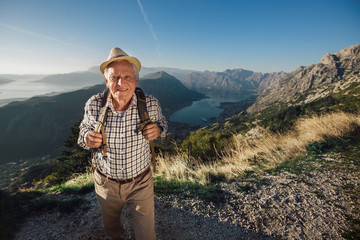 Happy old man just reaches the top of hill.Handsome senior man hiking, exploring.