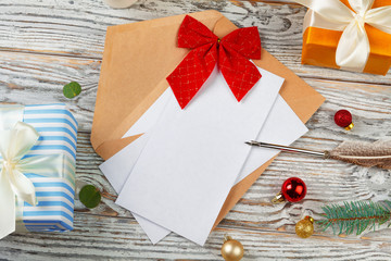 Close up of Christmas letter writing on yellow paper on wooden background with decorations