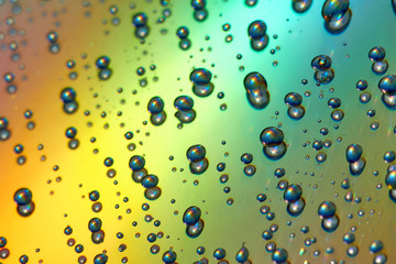 Water drops with reflection of the rainbow. Colorful abstract background. Blue, green, red and yellow abstract rainbow background. Closeup, selective focus
