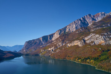 Aerial view of Lake Molveno, north of Italy. In the background rocky alps, blue sky. Autumn season....