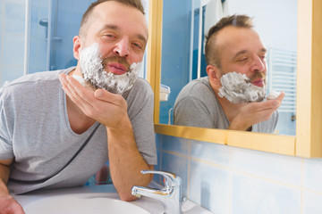 Guy shaving his beard in bathroom