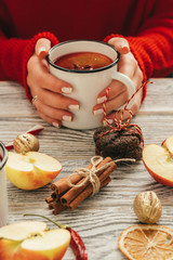 Cup of mulled wine in woman's hands on wooden table