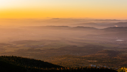 Obraz premium Beautiful colors of the sky at sunrise seen over the mountains and lowlands shrouded in fog. Characteristic landscape for the autumn season.