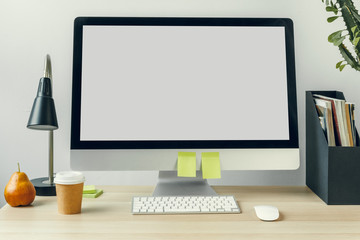 Computer monitor with mockup white screen on office table with supplies