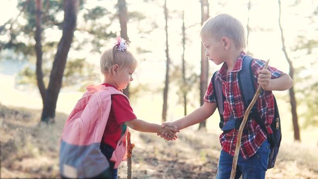 happy family little boy and girl tourists teamwork handshake scouts tourists slow motion video concept. brother and sister tourists shaking hands with backpacks hiking in the forest. group of kids