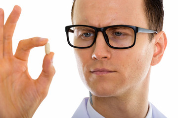Portrait of young handsome man doctor with eyeglasses holding medicine pills