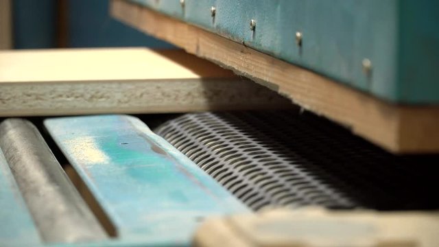 Particleboard elements after grinding process. Close up shot of grinder line. Wooden furniture components on production line.