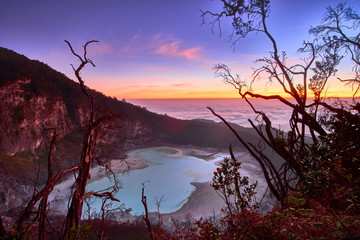 Beautiful scenery of sunrise over a crater lake on top of mountain with trees and colorful sky Indonesia