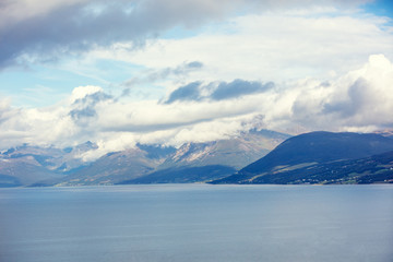 Fototapeta na wymiar Island on the horizon. Rocks in the sea. Beautiful rocky sea landscape with dramatic cloudy sky. Wild nature of Norway
