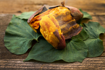 Roasted japanese sweet potato with smoke put on leaf and wooden background