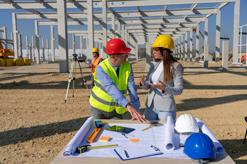 Mature Engineer and Female Architect Checking the Construction Blueprint on Construction Site