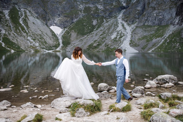 Cute young loving couple spending time in the mountains near the lake. A couple of newlyweds walk up alone. Honeymoon