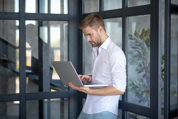Businessman standing near glass door with his laptop