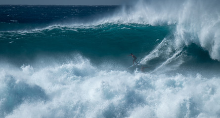 Two surfers sharing the giant wave at the famous Waimea Bay surf spot located on the North Shore of Oahu in Hawaii