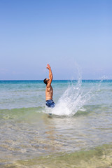 young muscular man posing and splashing around in the sea
