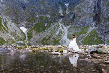 Fototapeta premium Pretty young woman spending time in the mountains near the lake. The bride walks up. Honeymoon