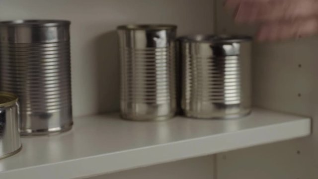Stacking aluminum tin cans  out of food cupboard shelf