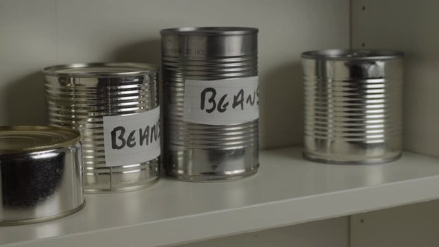 Getting tins of aluminum baked beans out of food cupboard shelf
