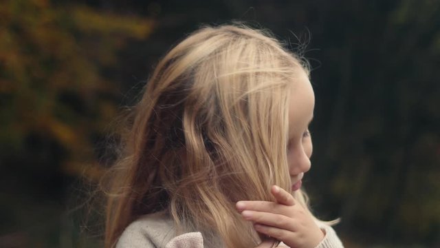 Cute little girl untangles long blond hair, portrait, slow motion.