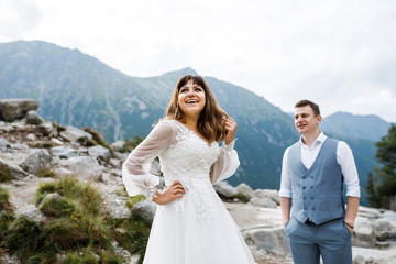 Cute young loving couple spending time in the mountains near the lake. A couple of newlyweds walk up alone. Honeymoon