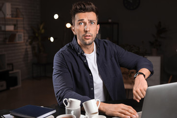 Tired man trying to meet deadline in office