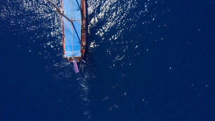 Tourists tour on old style pirate ship on calm clear drak blue sea Aerial top down view