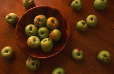 Top view of ripe garden apples in a bamboo bowl on wooden background