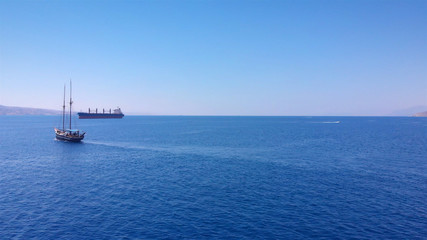 Tourists tour on old style pirate ship with large ships and desert mountains in the horizon