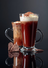 Hot chocolate with whipped cream and pieces of dark chocolate on a dark background.
