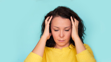 Young Asian girl scratches her hair on a blue background. headache