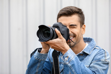 Young male photographer with camera outdoors