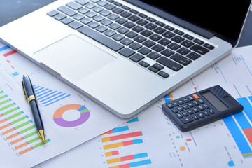 Laptop and pen with business charts, graphs, statistic and documents background for business and finance concepts