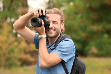 Young male photographer with camera outdoors - Powered by Adobe